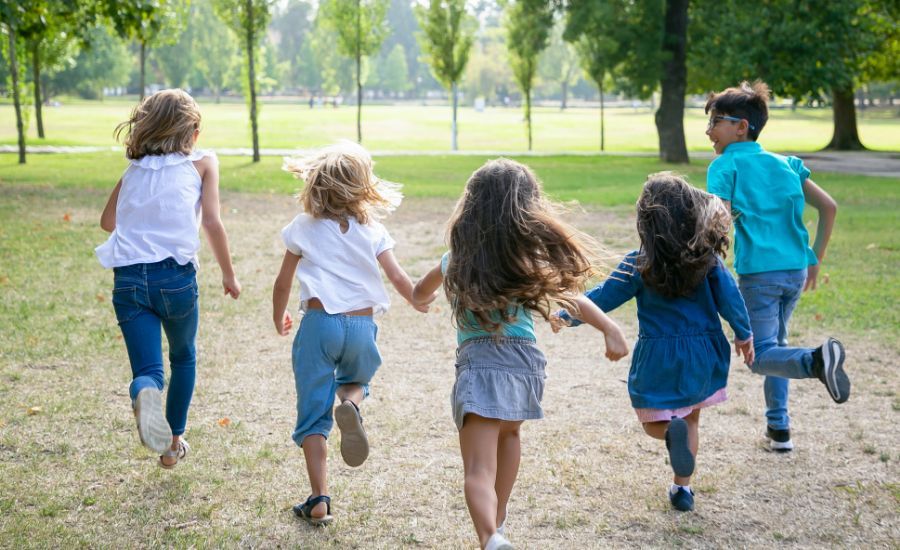 grupo-de-ninos-corriendo-juntos-sobre-la-hierba-con-carrera-en-el-parque-vista-posterior-de-cuerpo-entero-concepto-de-actividad-al-aire-libre-para-ninos