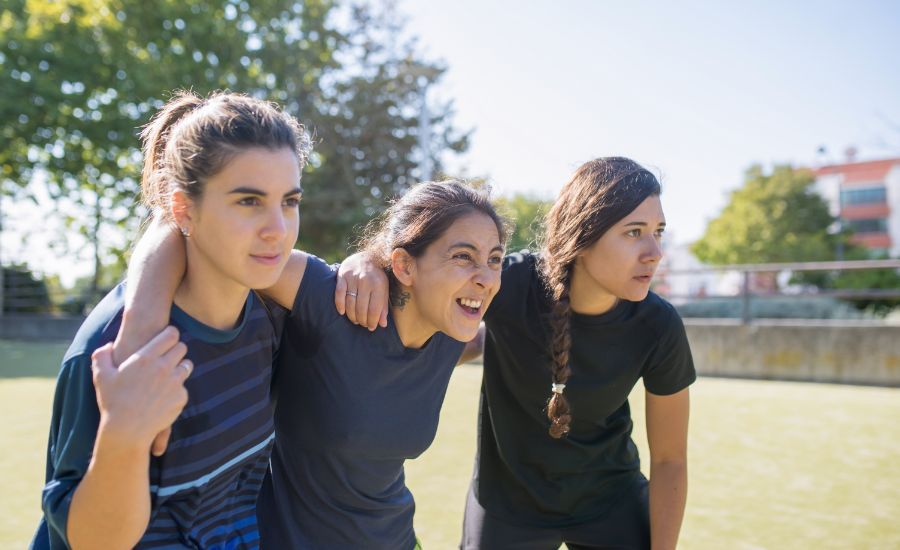 jovenes-amigas-en-el-campo-de-futbol-deportistas-con-diferentes-uniformes-mirando-competitivos-haciendo-muecas-deporte-ocio-concepto-de-estilo-de-vida-activo